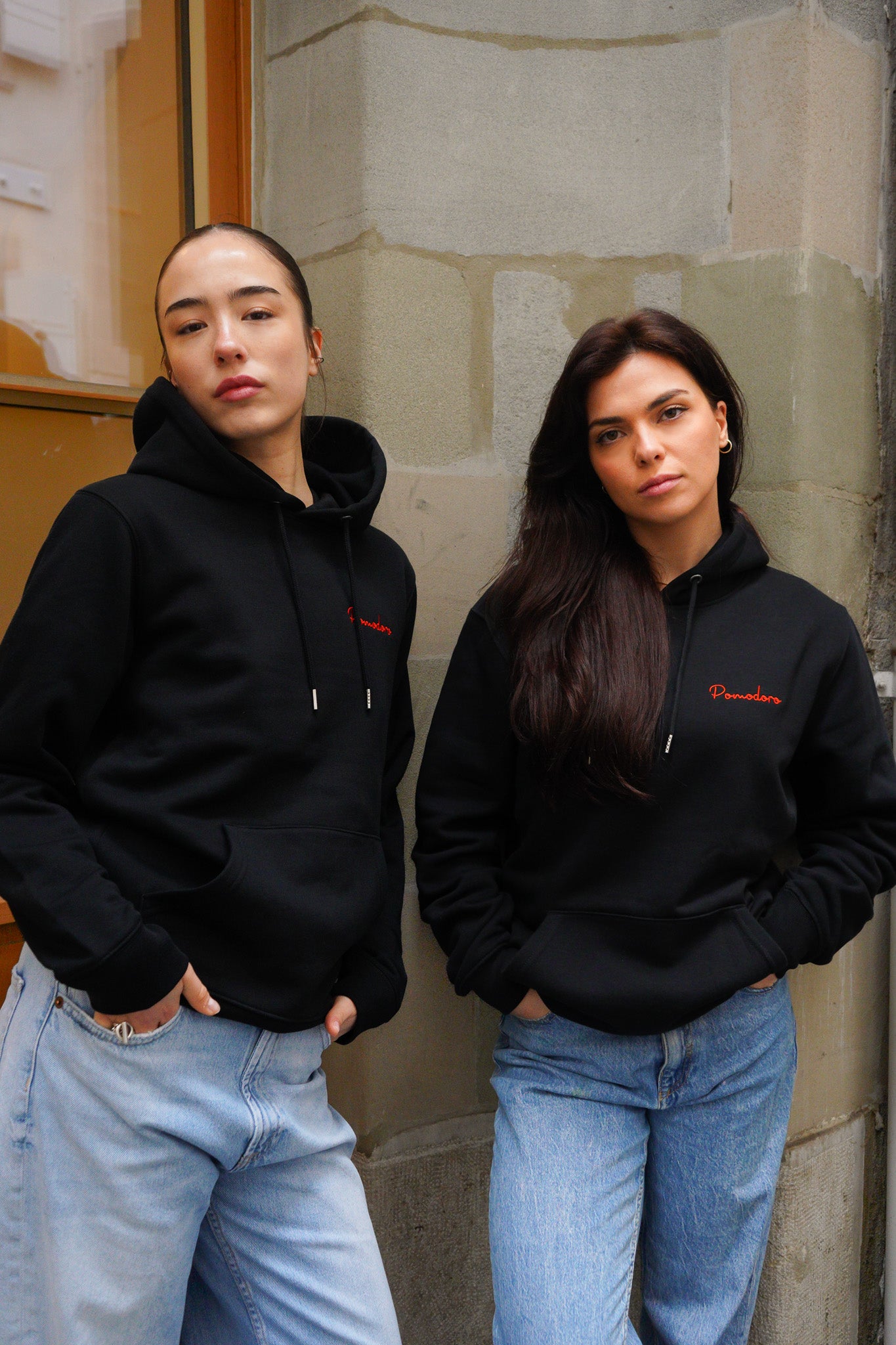 Look casual avec deux modèles portant le hoodie noir unisexe Pomodoro.